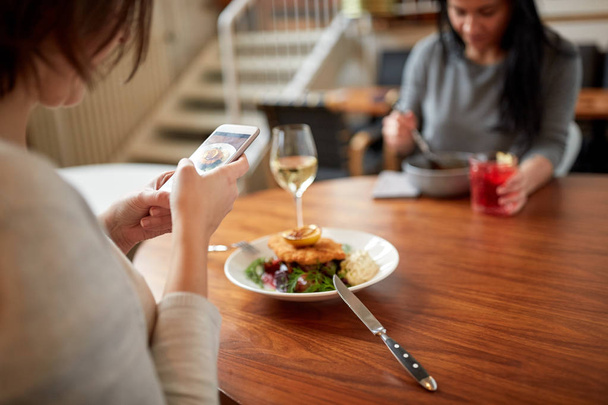 women with smartphones and food at restaurant - Фото, зображення