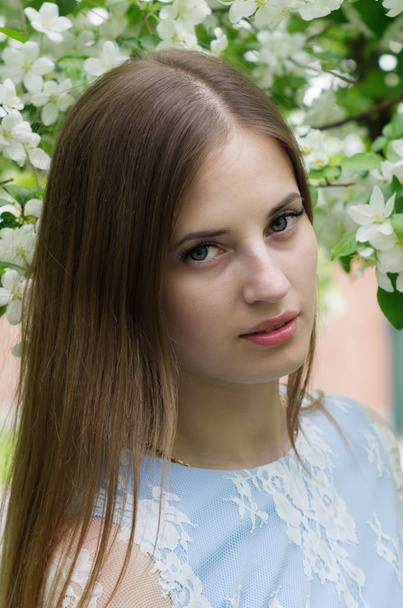 Girl posing against a background of flowering trees - Foto, afbeelding