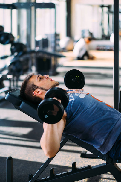 joven hombre guapo haciendo ejercicio con pesas en un gimnasio de fitness
 - Foto, imagen