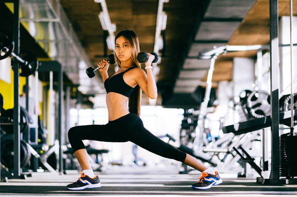 Hermosa mujer fitness levantando pesas. Fitness chica deportiva haciendo ejercicio en el gimnasio
 - Foto, Imagen