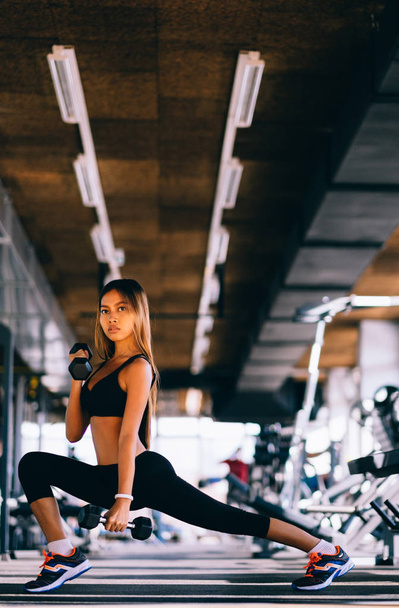 Beautiful fitness woman lifting dumbbells . Fitness sporty girl exercising in gym - Photo, image