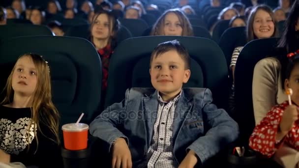 Beautiful boy and many little girls watching movie at the cinema. Close up portrait. - Footage, Video