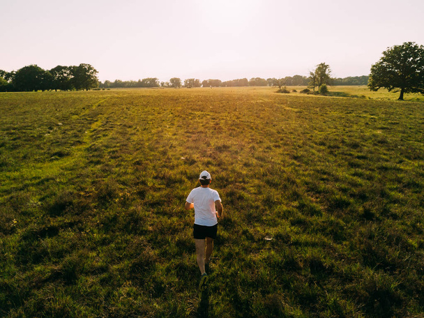  Een man loopt op het platteland bij zonsondergang. - Foto, afbeelding