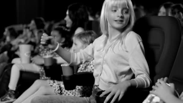 Černobílý obrázek. Roztomilá dívka s její přátel citově sledování filmu v kině. - Záběry, video