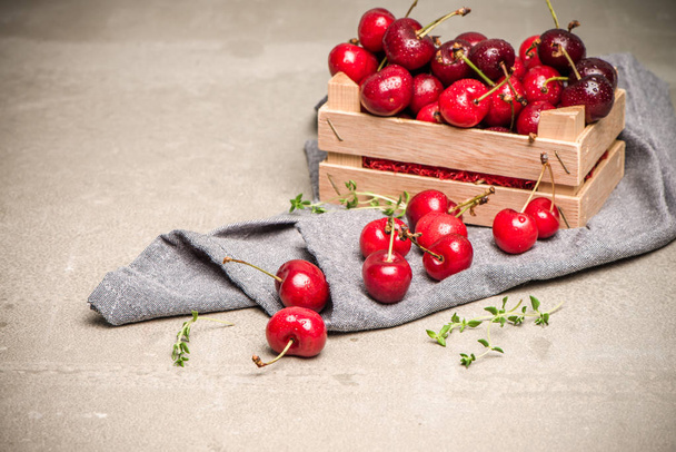 Red ripe cherries in small wooden box - 写真・画像