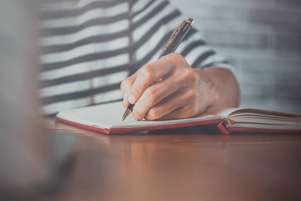 Primo piano di persone scrittura a mano su notebook su tavolo di legno - Foto, immagini