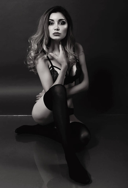 beautiful woman with dark hair in black lingerie posing at bedro - Valokuva, kuva