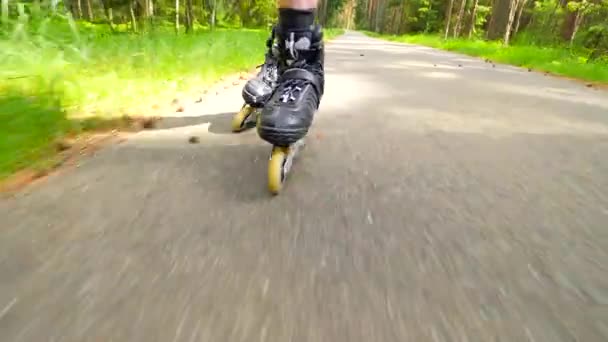 Outdoor shuffle inline skating. Mans legs roller skating on forest asphalt path. Close up view to quick shuffle movement of inline boots. - Footage, Video