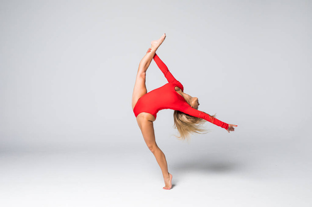 junge schöne Tänzerin im roten Badeanzug posiert auf einem isolierten weißen Studiohintergrund - Foto, Bild