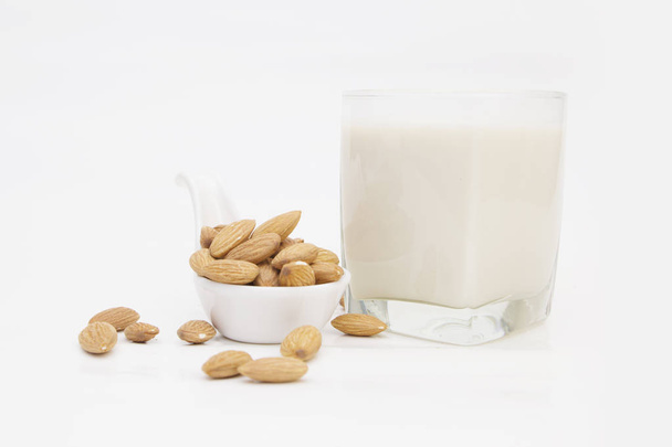mandlové mléko v lahvi s ořechy izolovaných na bílém pozadí - Fotografie, Obrázek