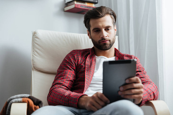 Serious young bearded man using tablet computer. - Photo, image