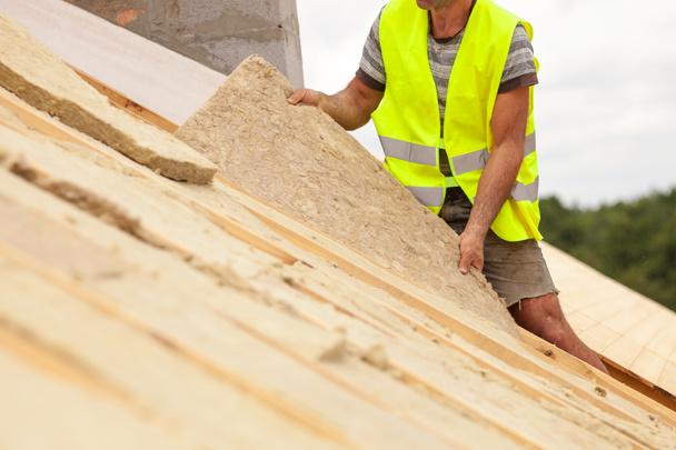 Dakdekker bouwer werknemer installeren van dak isolatiemateriaal op nieuw huis in aanbouw. - Foto, afbeelding