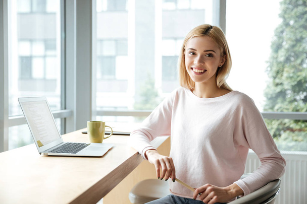 Cheerful lady sitting in office coworking while using laptop - Photo, Image