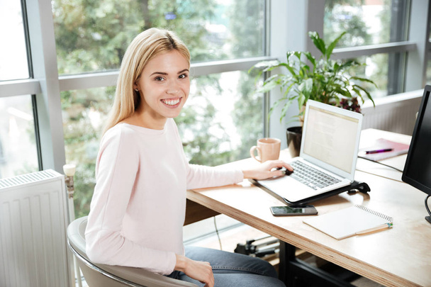 Cheerful lady sitting in office coworking using laptop - Foto, imagen