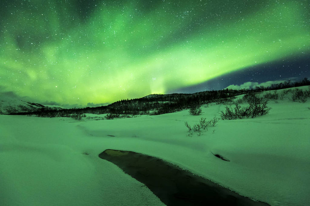 Nordlichter über einem Wasserstrom in einer Winterlandschaft. - Foto, Bild