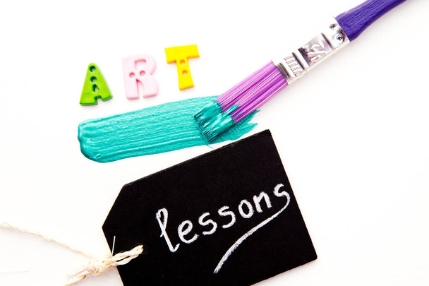 Искусство - буквы с Пайнтом и кистью на белом фоне с уроками на метке на доске
 - Фото, изображение