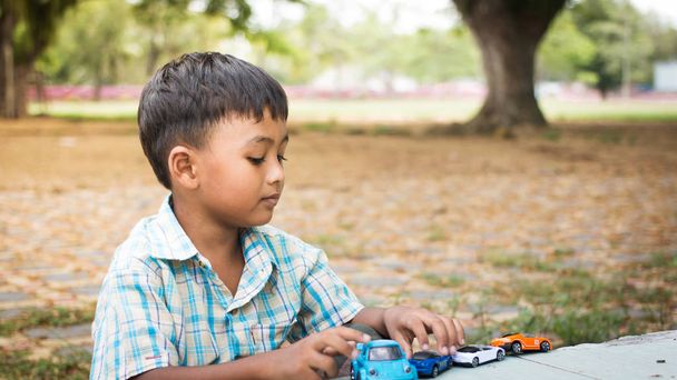 милый маленький мальчик играет в игрушечную машину в зеленом парке
 - Фото, изображение