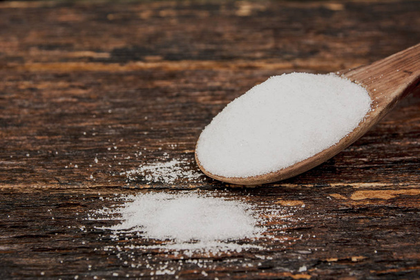 Sugar on a wooden spoon on wooden table  - Foto, Bild