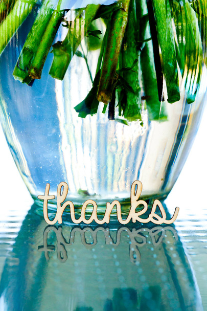 wooden word thanks reflected in glass table with flower stems in vase in background - Φωτογραφία, εικόνα