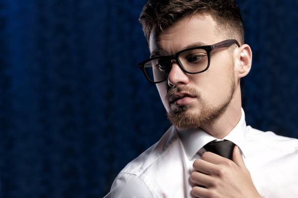 Portrait of handsome young man with glasses and white shirt on dark background - Foto, immagini