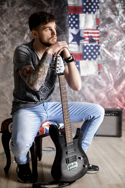 Young handsome musician with electric guitar on dark background - Fotoğraf, Görsel