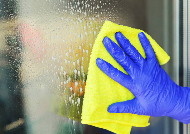Woman cleaning a window with yellow cloth.  - Photo, Image