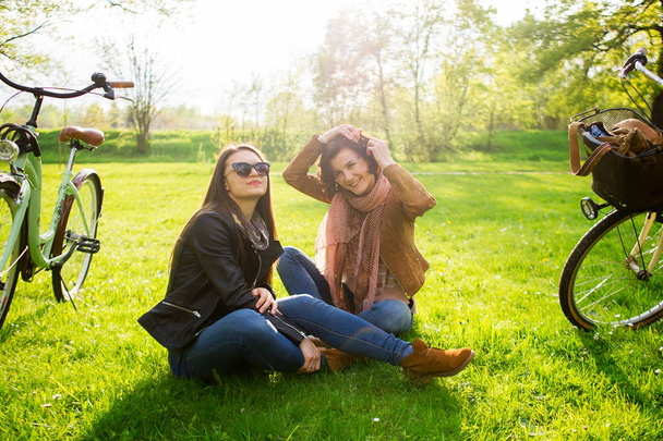 Charming young women sit on a green lawn in the spring park. - 写真・画像
