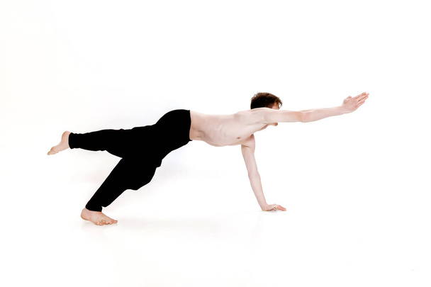 Young man doing yoga exercises. Studio shot on white background - 写真・画像
