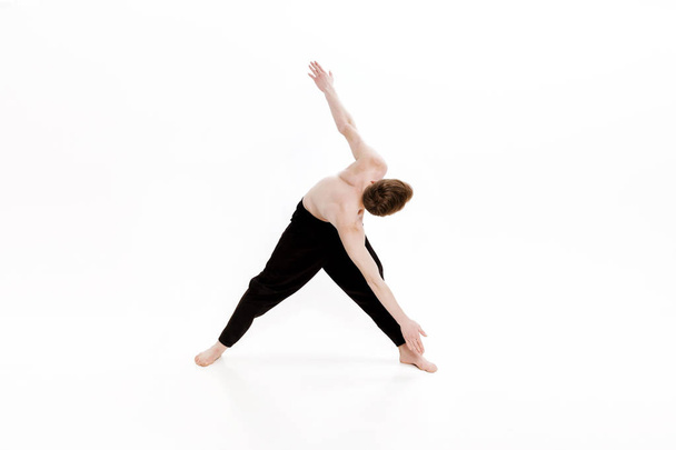 Young man doing yoga exercises. Studio shot on white background - Foto, afbeelding