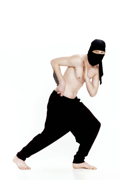 ninja hombre sostiene cuchillo y está listo para atacar sobre fondo blanco
 - Foto, imagen