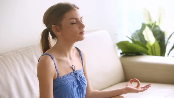Beautiful young woman meditating at home, breathing air, practicing yoga - Imágenes, Vídeo
