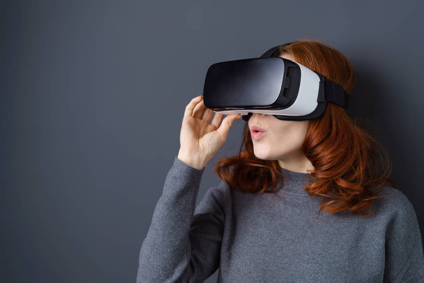 Cute amazed young woman wearing a VR headset - Foto, afbeelding
