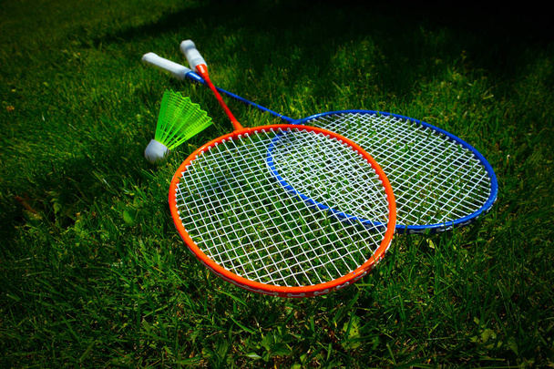 Two badminton racket on the sunny bright grass green fresh backg - Фото, изображение