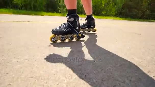Very close up side view to working inline skates. Easy skating on the smooth  asphalt. Close up view to quick movement of black four wheels inline boots. - Footage, Video