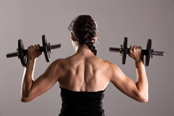 girl in sexy black dress lifting weights - Zdjęcie, obraz