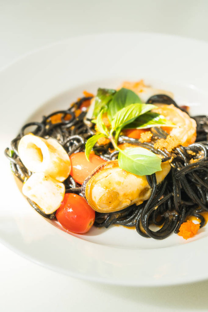 schwarze Spaghetti mit Meeresfrüchten in weißem Teller - Foto, Bild