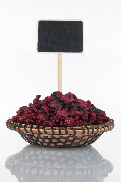 Plate with a bunch of dried cranberry and its reflection and price tag, pointer. - Foto, afbeelding