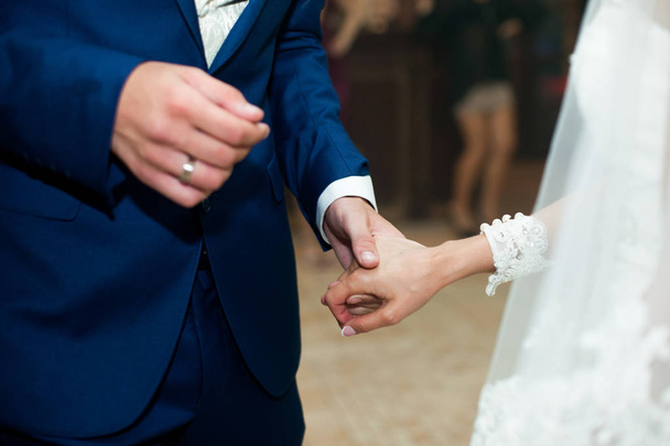 A closeup of newlyweds hands held together during a dance - Foto, afbeelding