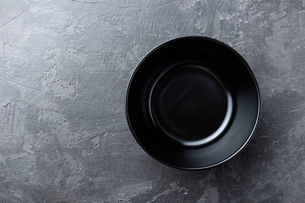 Empty black soup plate on dark grey background, top view - Foto, Imagen