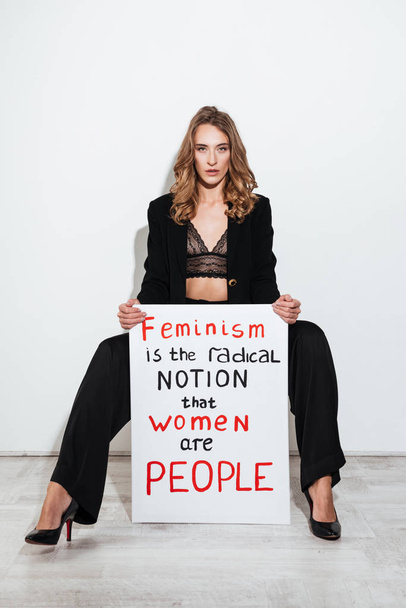 Caucasian lady holding blank with text about feminism - Foto, Bild