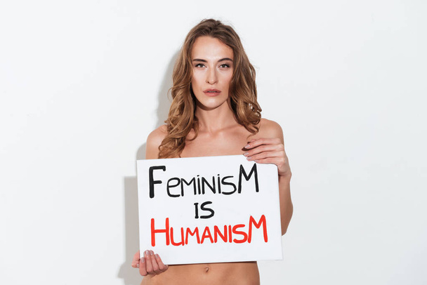 Serious woman feminist holding nameplete near breast - Foto, imagen