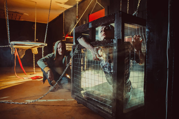 Bloody maniac and his female victim in the cage. - Valokuva, kuva