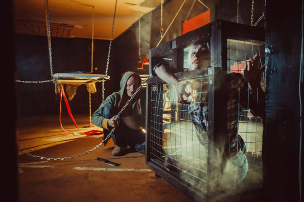 Bloody maniac and his female victim in the cage. - Foto, Imagen