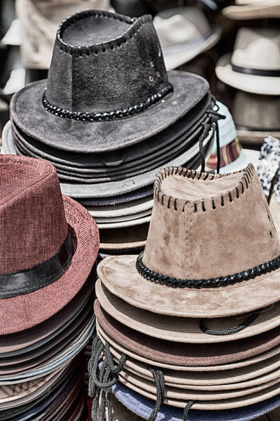 vanhoilla markkinoilla paljon värillisiä hattuja
  - Valokuva, kuva