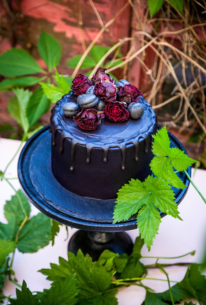 Готический черно-розовый торт на деревянном торте стоит в тайном саду
 - Фото, изображение