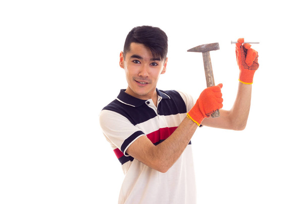 Hombre con guantes naranjas sosteniendo martillo y clavo
 - Foto, imagen