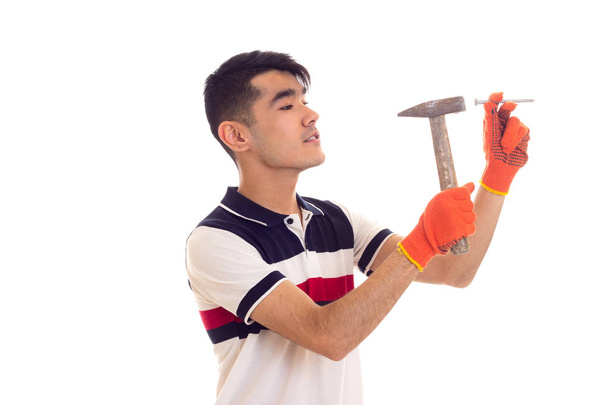 Mann in orangefarbenen Handschuhen mit Hammer und Nagel - Foto, Bild