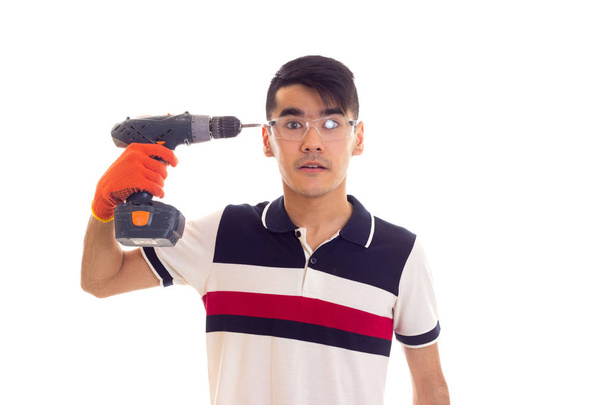 Молодой человек в перчатках и очках держит электрическую отвертку
 - Фото, изображение