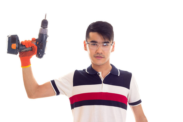 Молодой человек в перчатках и очках держит электрическую отвертку
 - Фото, изображение