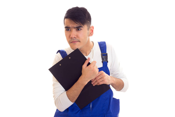 Young man in blue overall holding pen and folder - Photo, Image